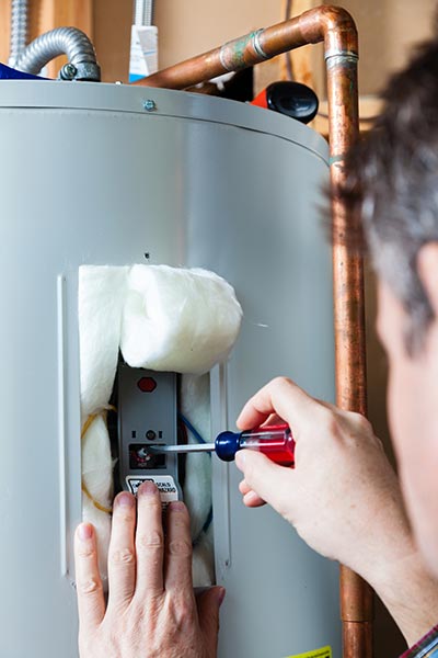 Technician Inspecting a Leaking Connection During Water Heater Repair in Montgomery, IN